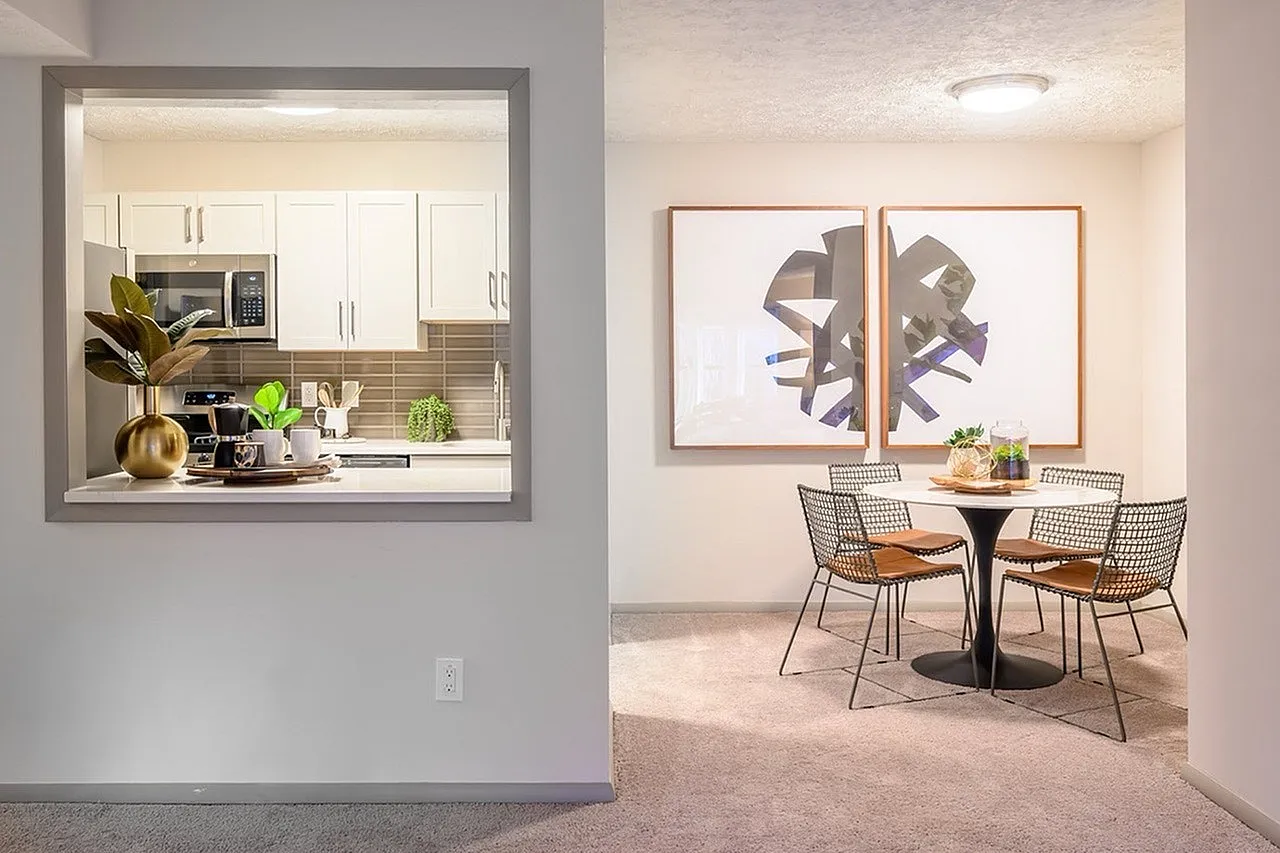 Kitchen with white shaker cabinetry, stainless appliances, brown tile backsplash, dining area with round table and wire chairs