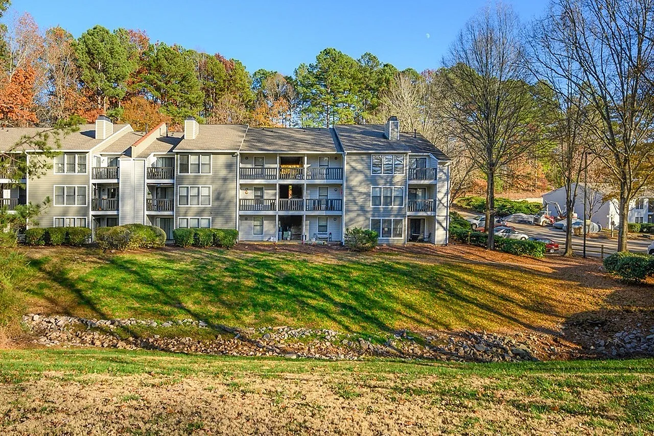 Multi-story residential building, manicured lawn, autumn foliage, balconies, landscaping