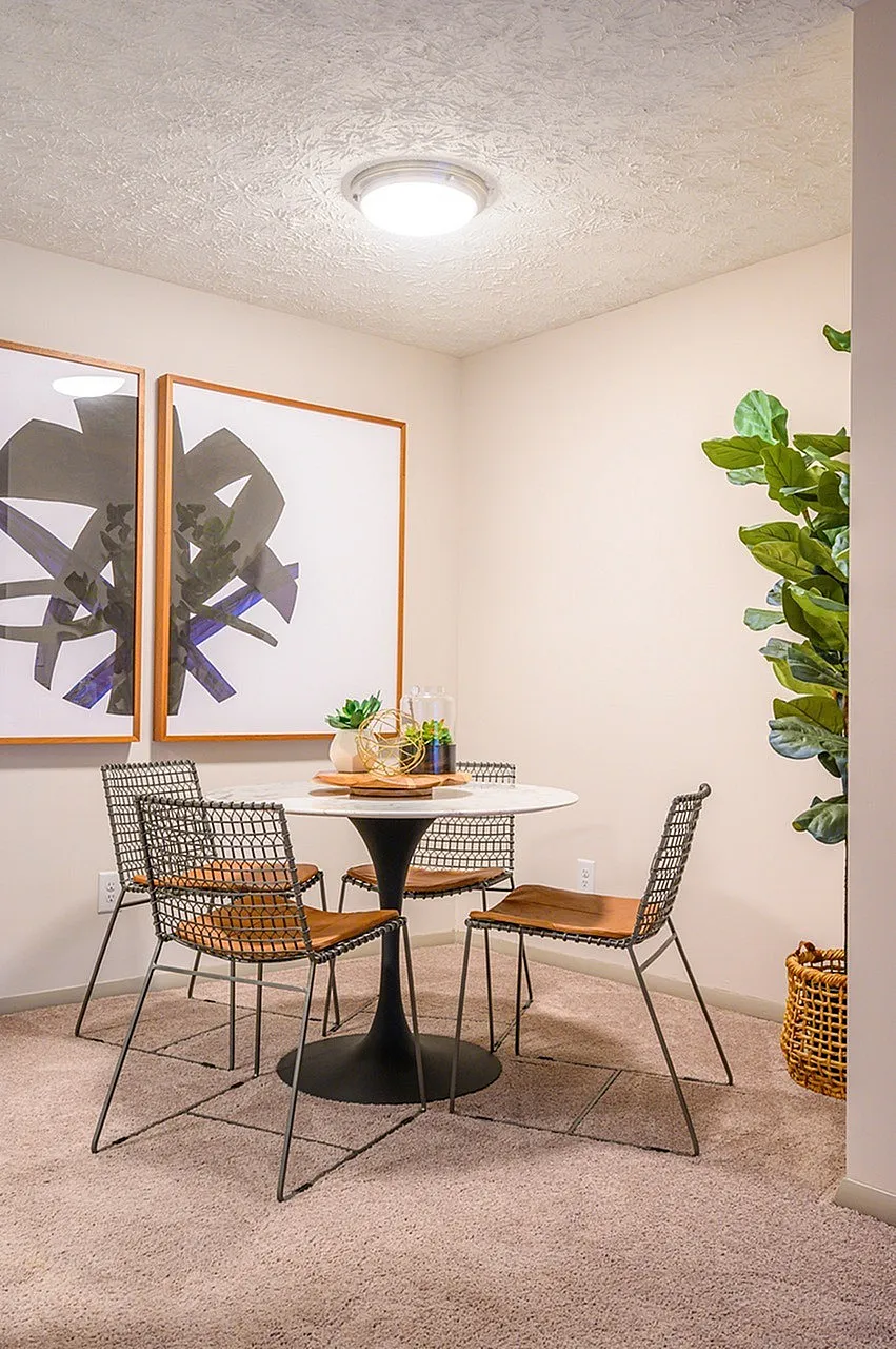 Meeting room, black pedestal table, woven chairs, framed artwork, potted plants