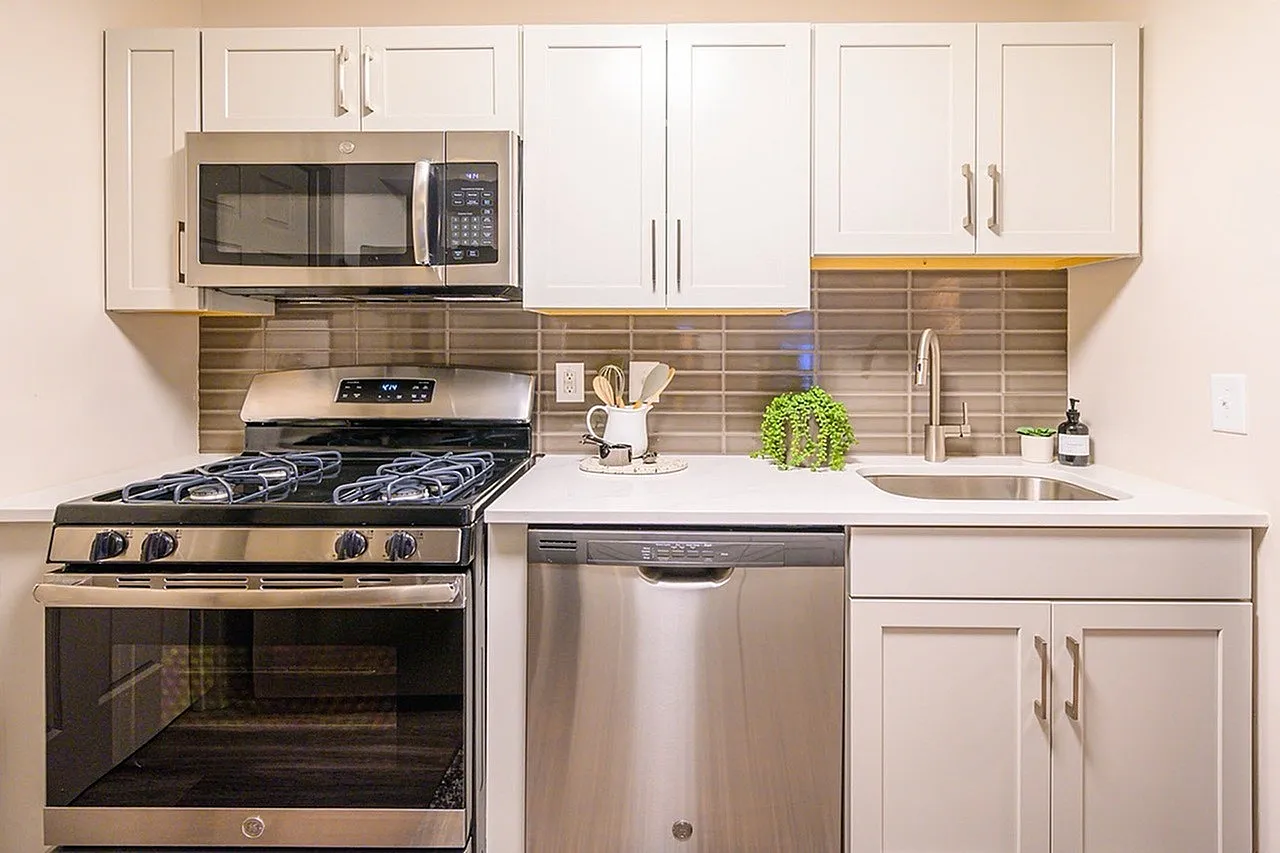 Kitchen, white shaker cabinetry, stainless steel appliances, tan tile backsplash, quartz countertops