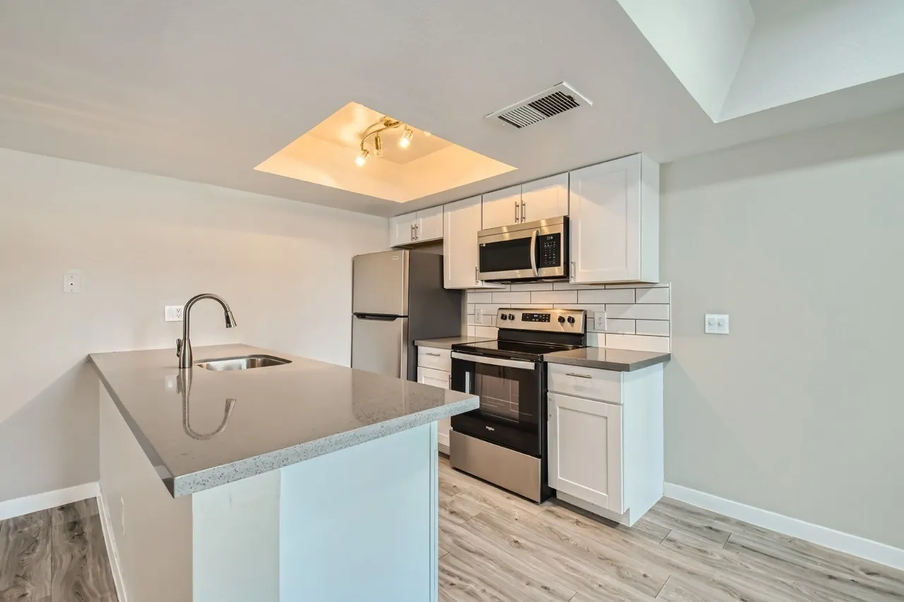 Kitchen peninsula with sink, subway tile, and track lighting