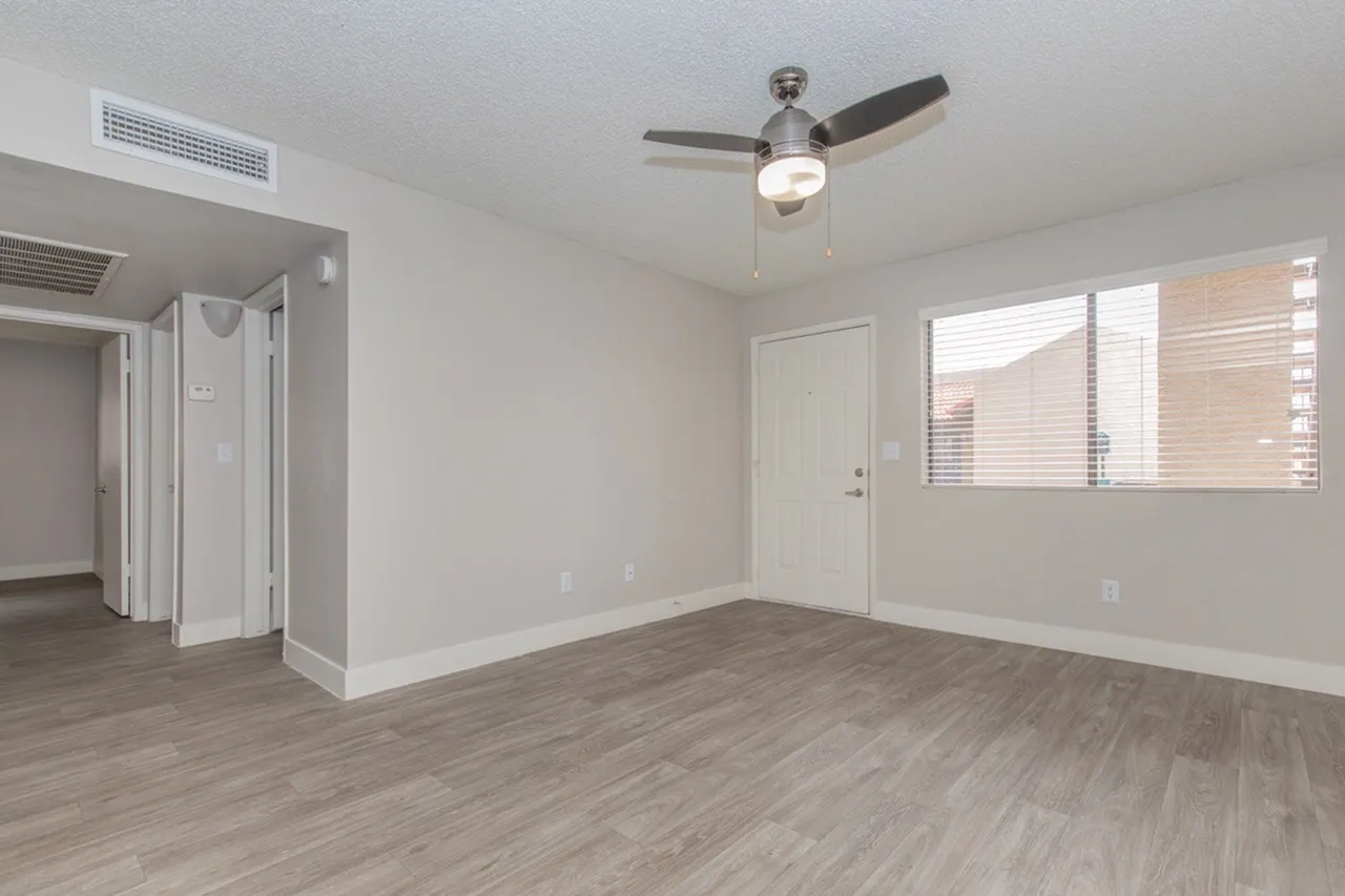 Living room with ceiling fan, front entry, and window
