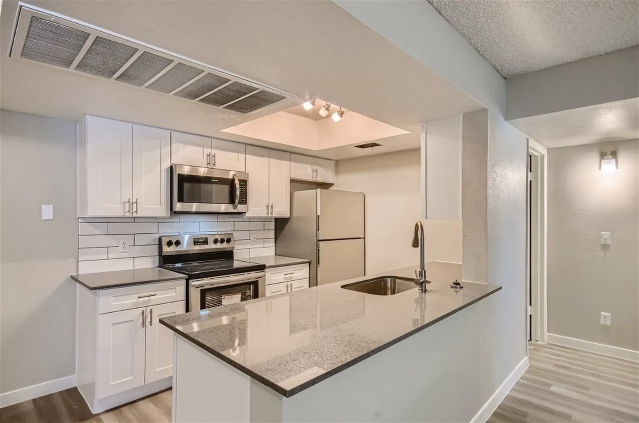 Subway tile backsplash, speckled gray countertops, and stainless steel appliances