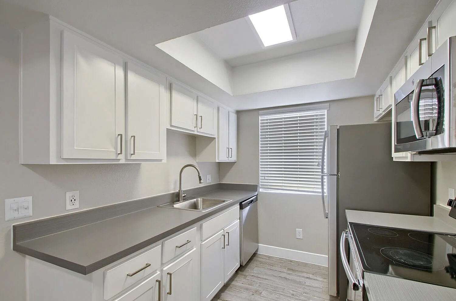 Kitchen sink beneath window with gray countertops
