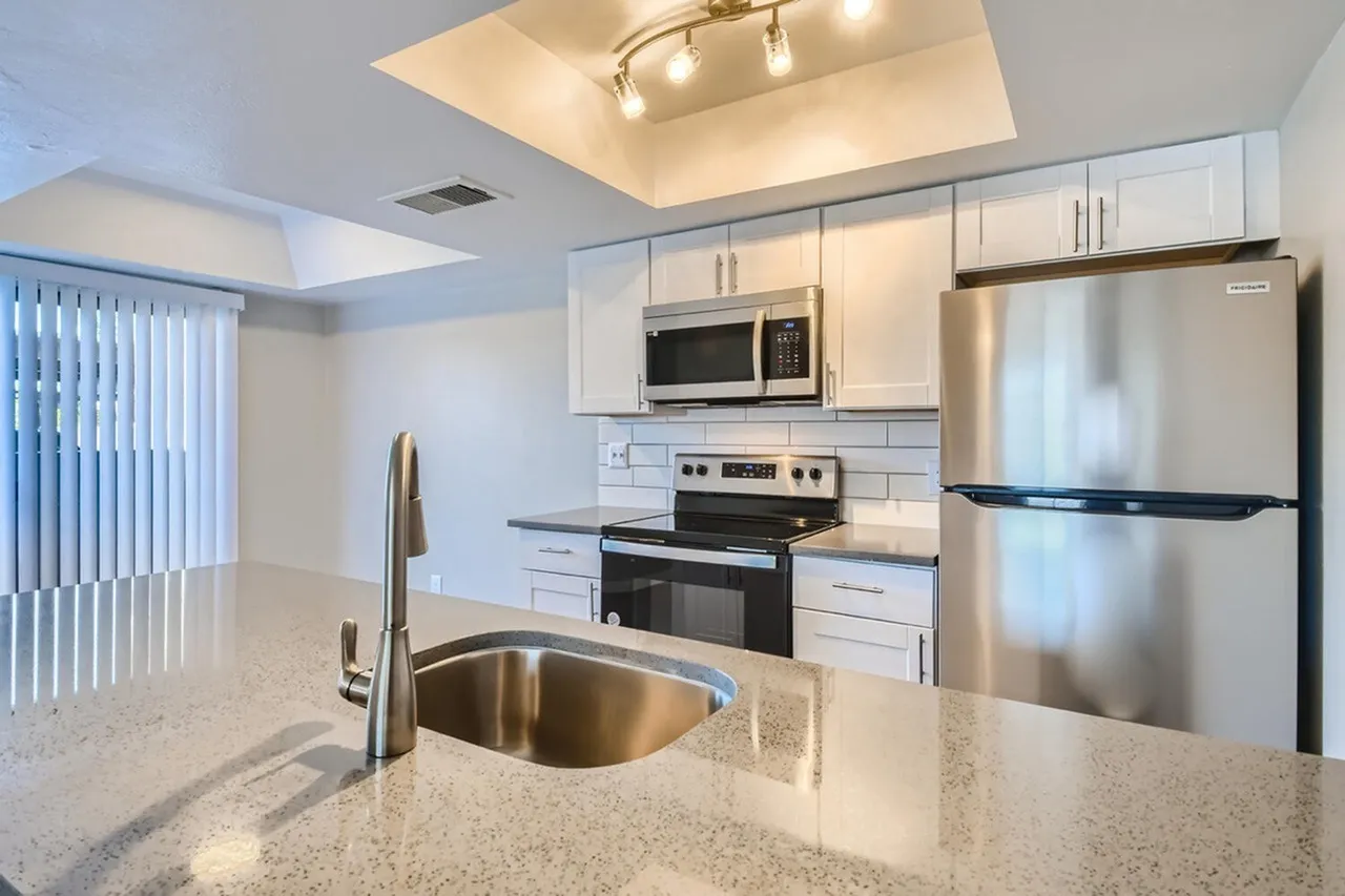 Stainless steel sink and gooseneck faucet on speckled countertop
