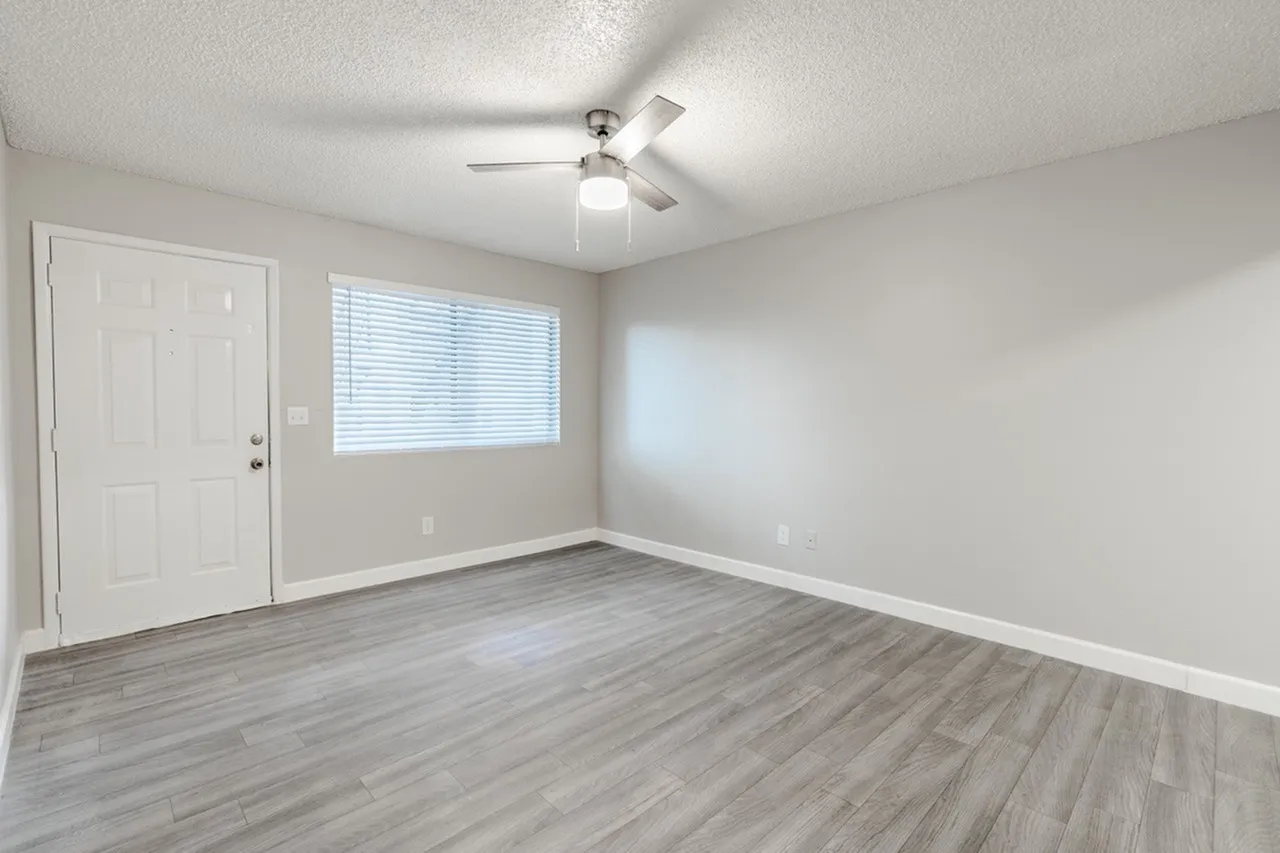 Living room with window, ceiling fan, and neutral walls
