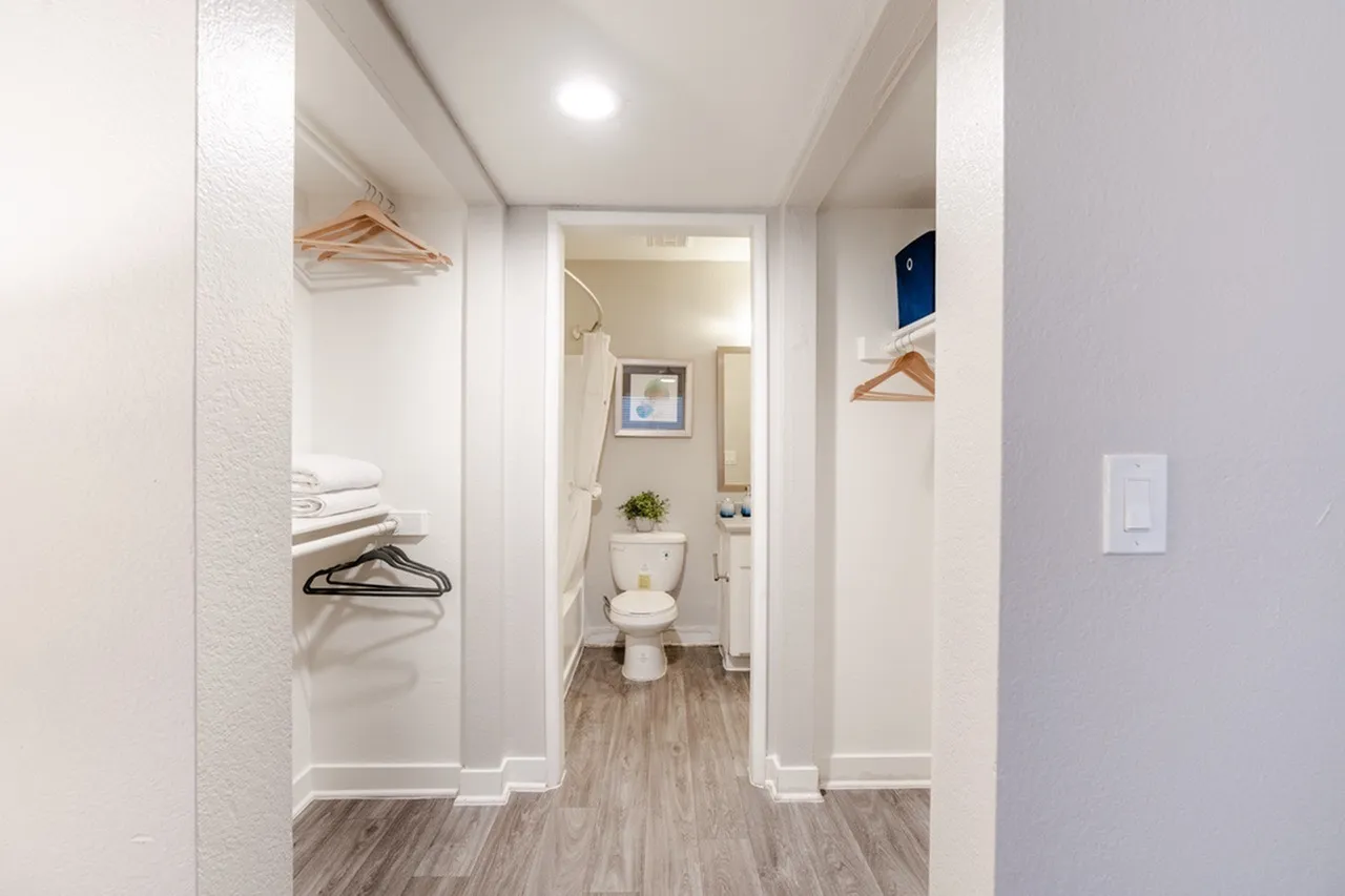 Walk-in closet with hanging rod leading to bathroom