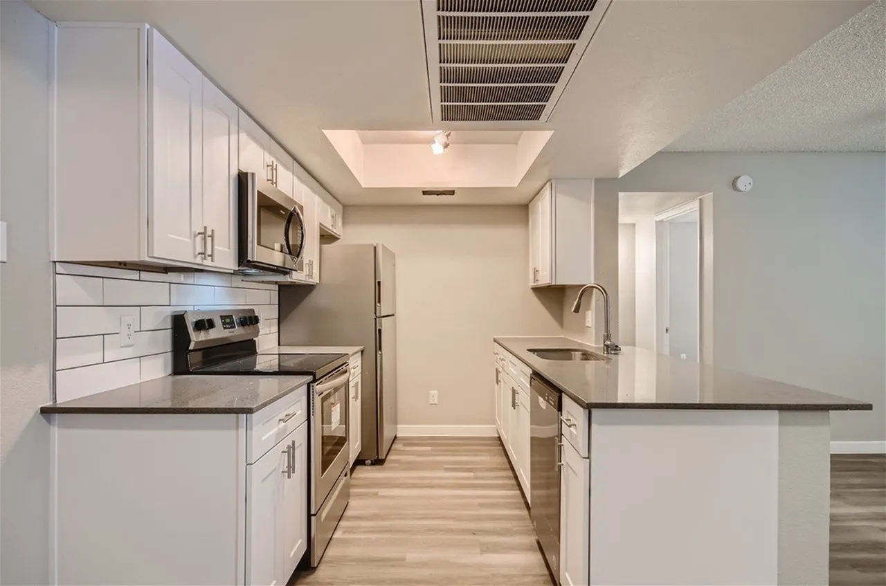Galley kitchen with track lighting and white shaker cabinets