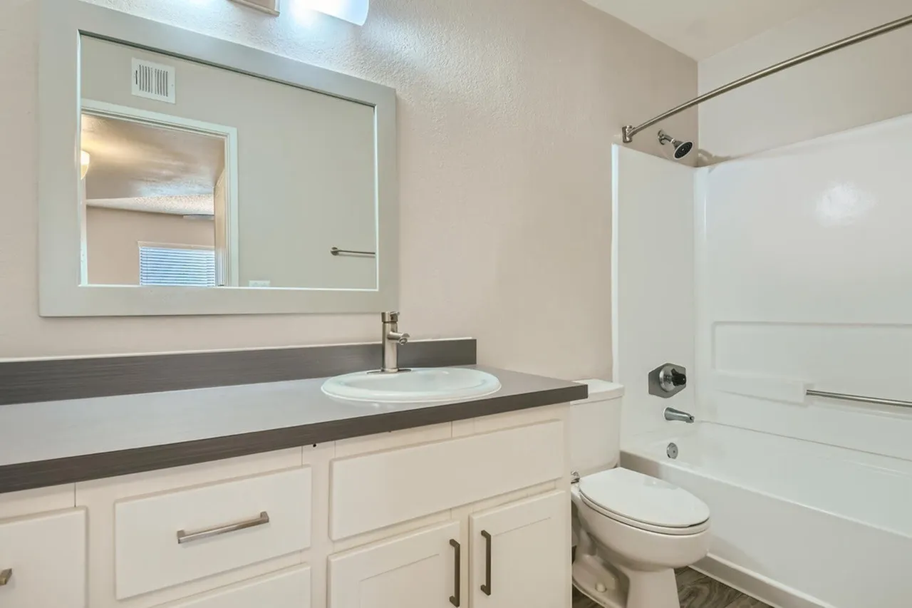 Framed mirror, white vanity, and tub-shower