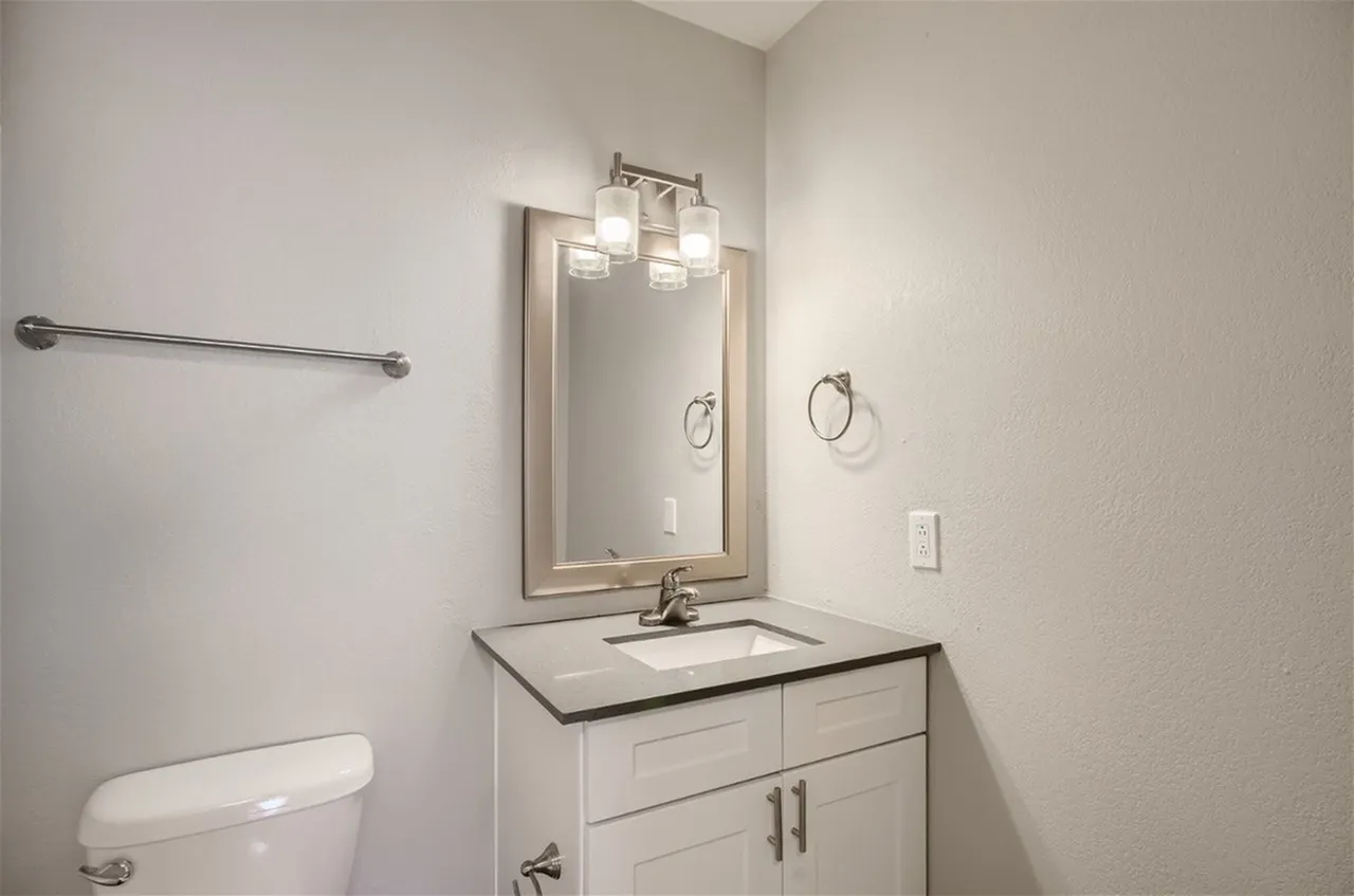 Second bath with gray countertop and framed mirror
