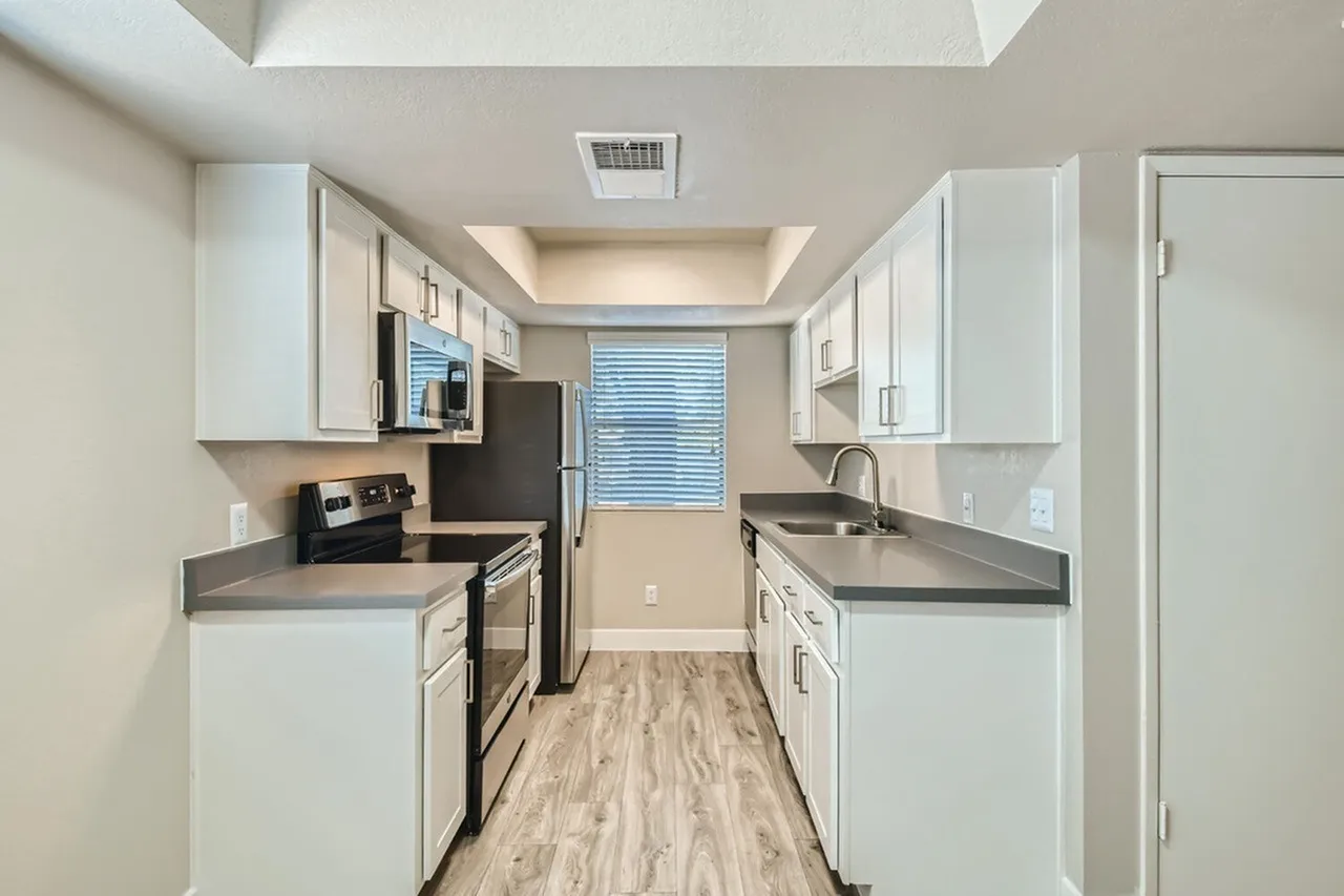 Galley kitchen with white cabinets and dark gray countertops