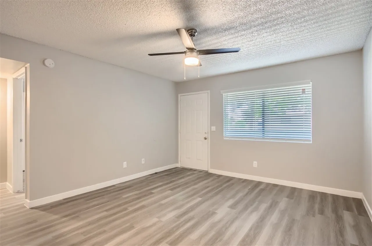 Living room with front door, window, and ceiling fan