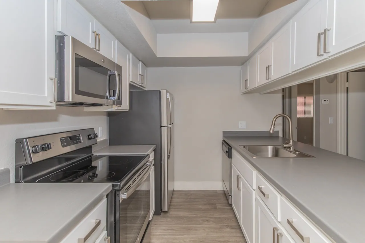 Stainless steel appliances and white cabinetry with gray counters