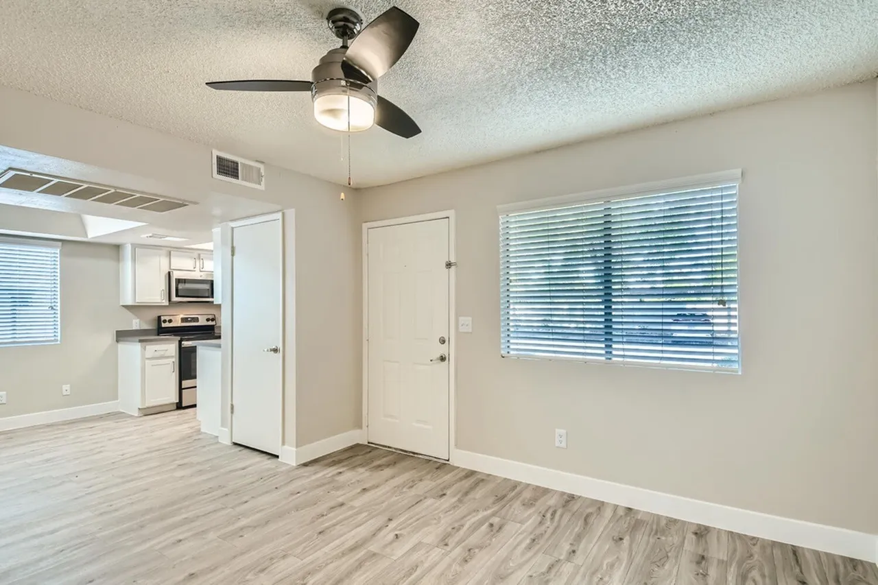 A2 Gold living room with ceiling fan, entry door, and wood-style plank flooring