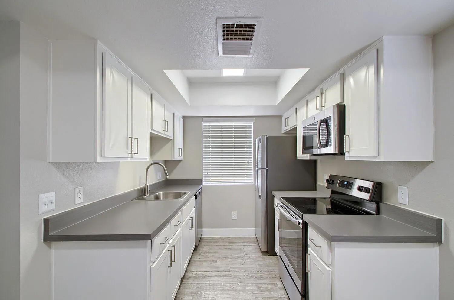 Galley kitchen with white cabinets and stainless steel appliances