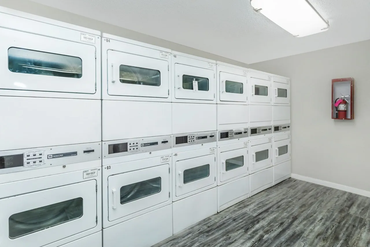 Laundry room, white dryers and washers, gray tile flooring, fire extinguisher