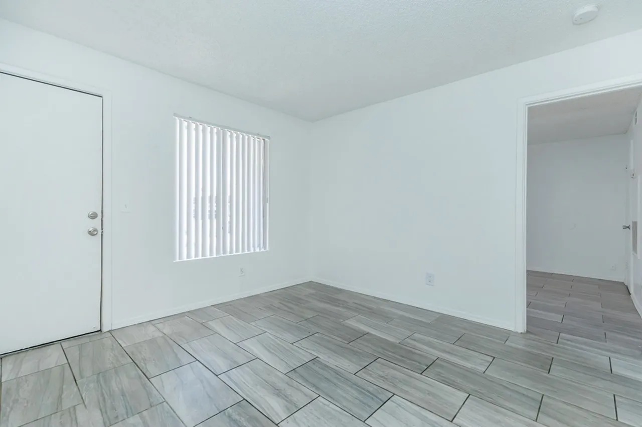 Bedroom, wood-style plank flooring, vertical window blinds, white walls, entry door