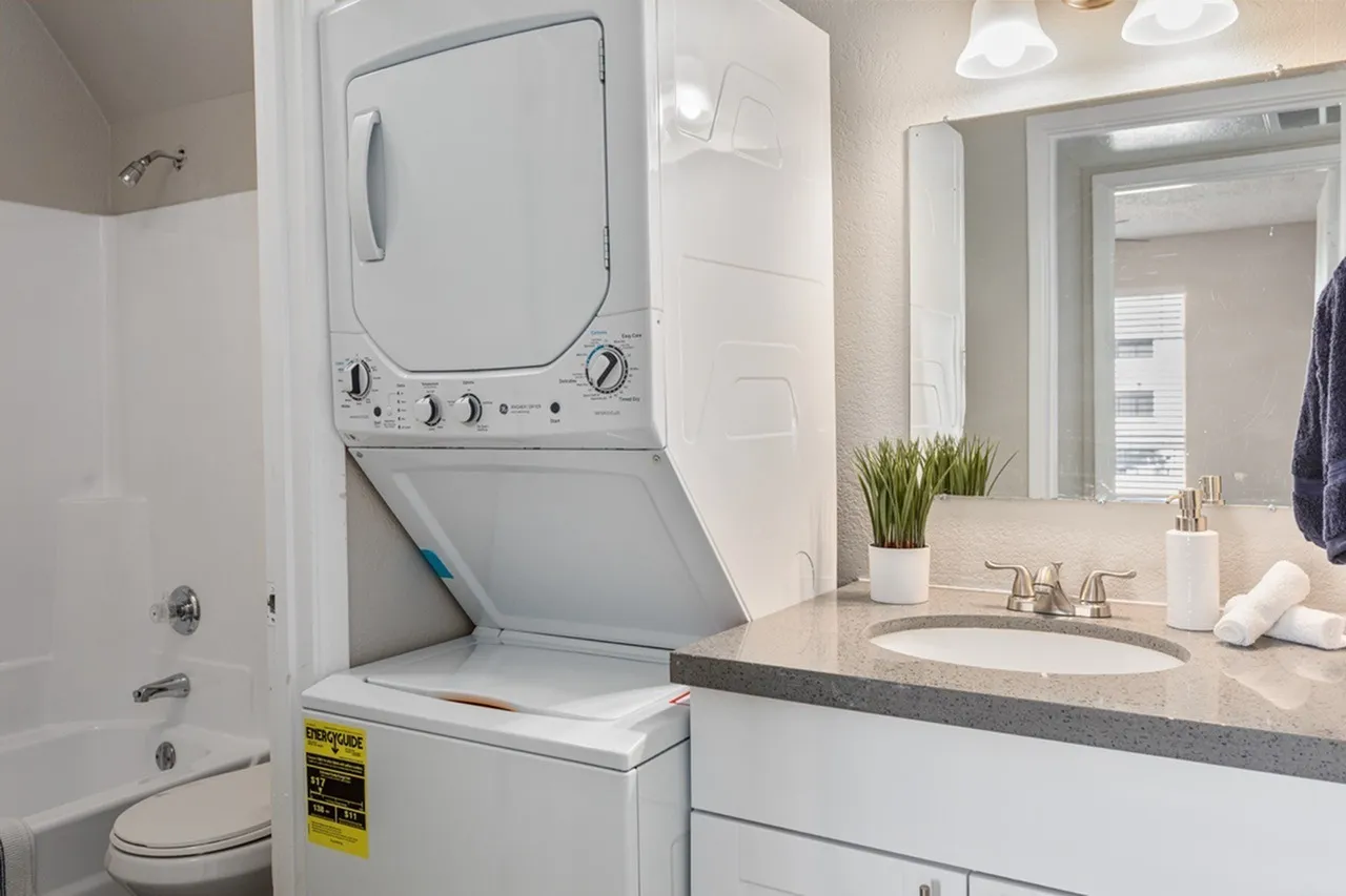 Bathroom, stacked washer dryer, gray quartz countertops, white cabinetry