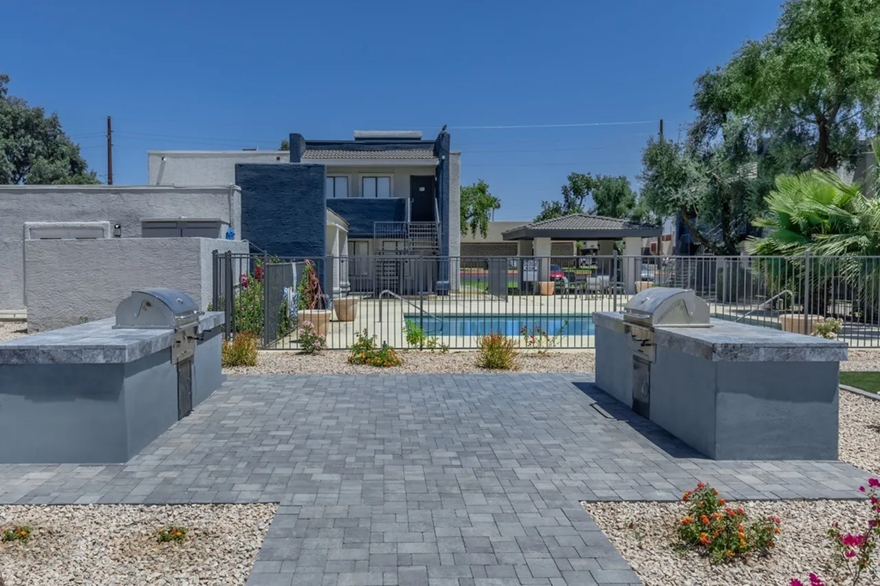 Paved entry courtyard, gray concrete pavers, planter boxes, pool visible beyond gate, Glendale