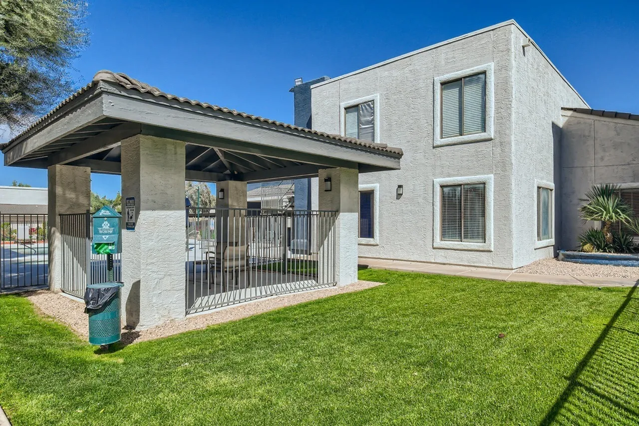 White modern home with covered porch, white metal railing, manicured lawn, concrete driveway
