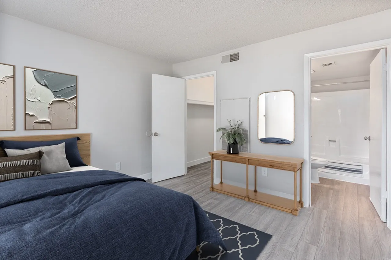 Primary bedroom, wood-style plank flooring, navy bedding, ensuite bathroom entry