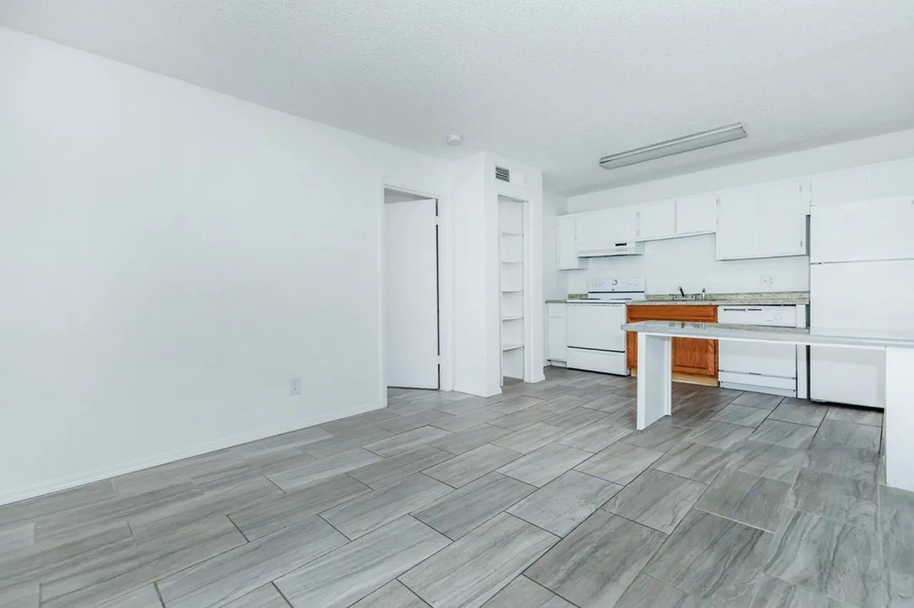 Kitchen, white cabinetry, wood-style plank flooring, white island, stainless appliances