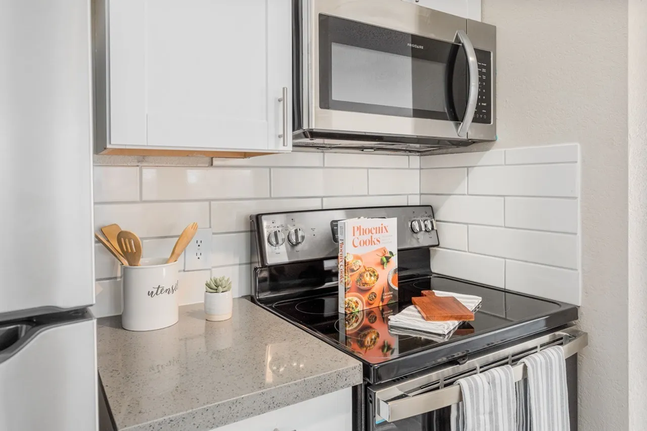 Kitchen, white shaker cabinetry, gray quartz countertops, stainless steel microwave and range, subway tile backsplash