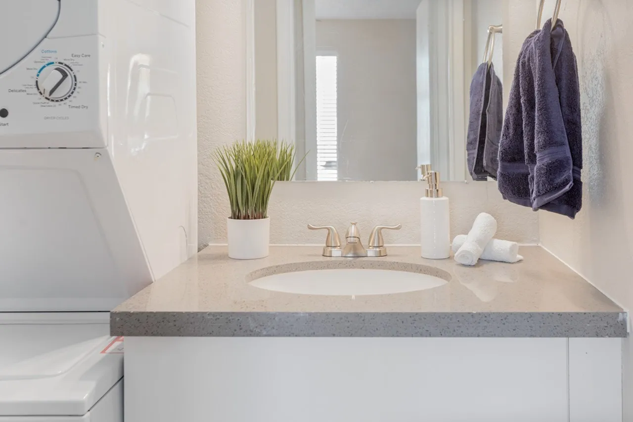 Bathroom, white vanity, gray quartz countertop, round sink, brass faucet, mirror, towel bar