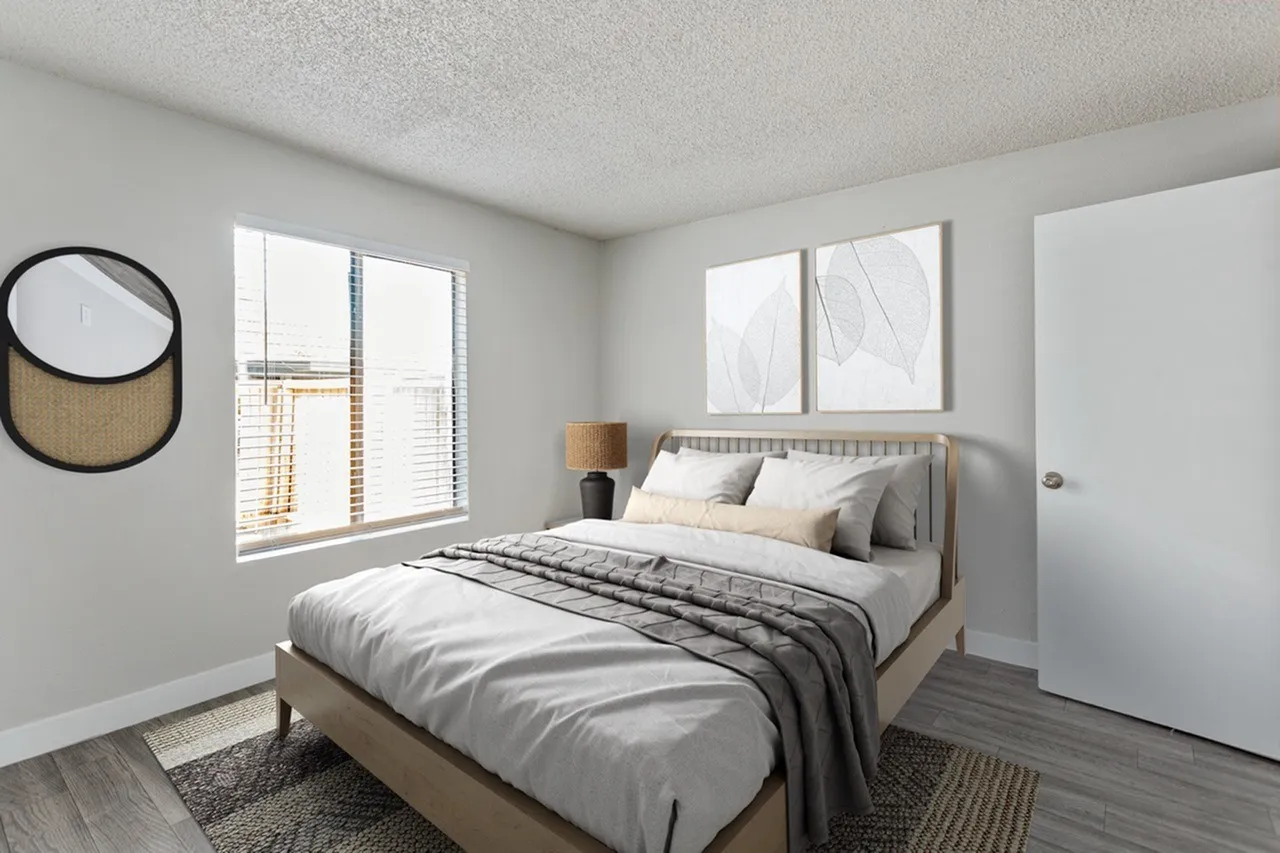Primary bedroom, wood-style plank flooring, gray upholstered bed frame, natural light from windows