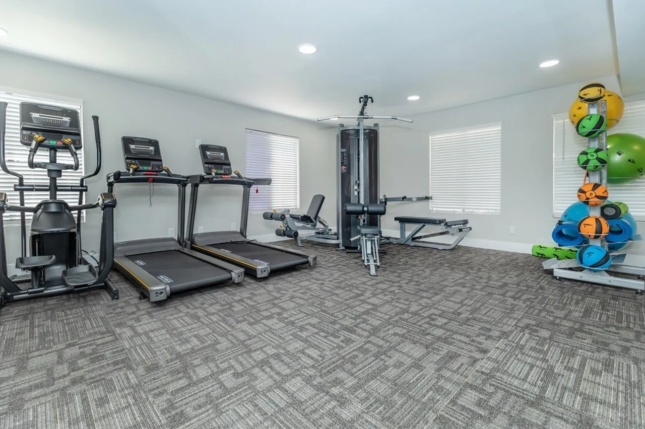 Fitness center, treadmills, elliptical machine, weight rack, gray tile flooring