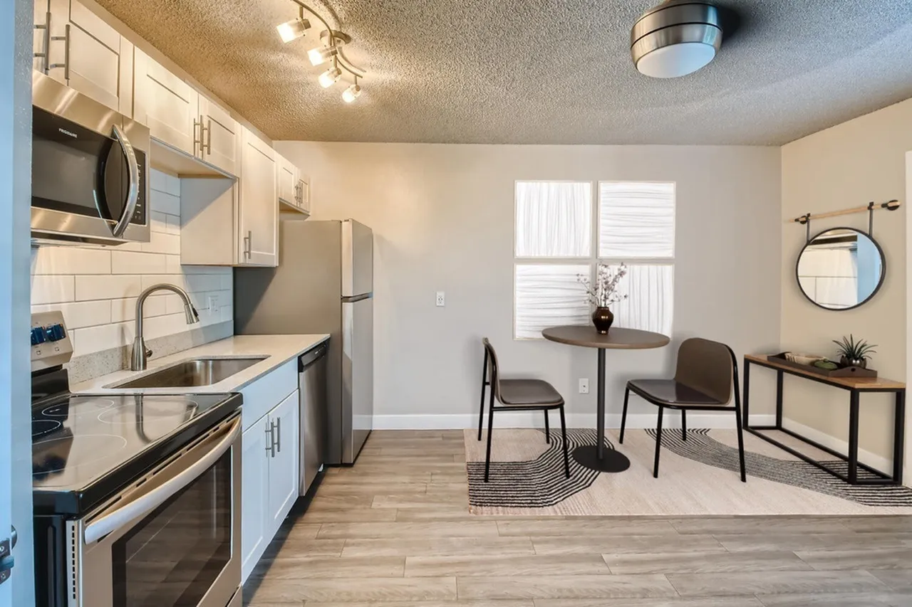 Kitchen and dining area, white shaker cabinetry, stainless appliances, wood-style plank flooring, dining table