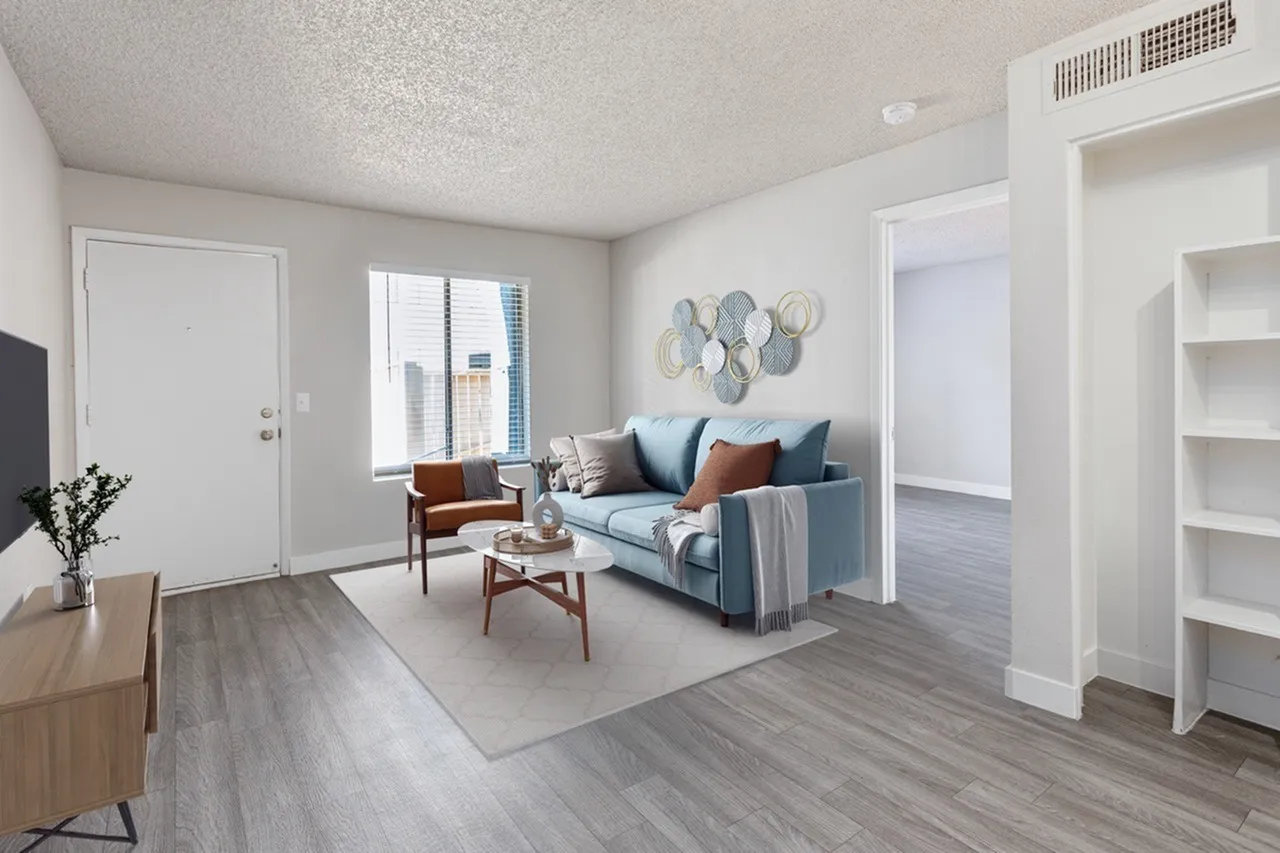 Living room, blue upholstered sofa, wood-style plank flooring, decorative wall plates, floor-to-ceiling windows