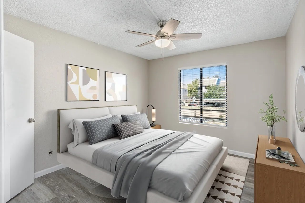 Primary bedroom, gray upholstered bed, wood-style plank flooring, ceiling fan, window with black frame