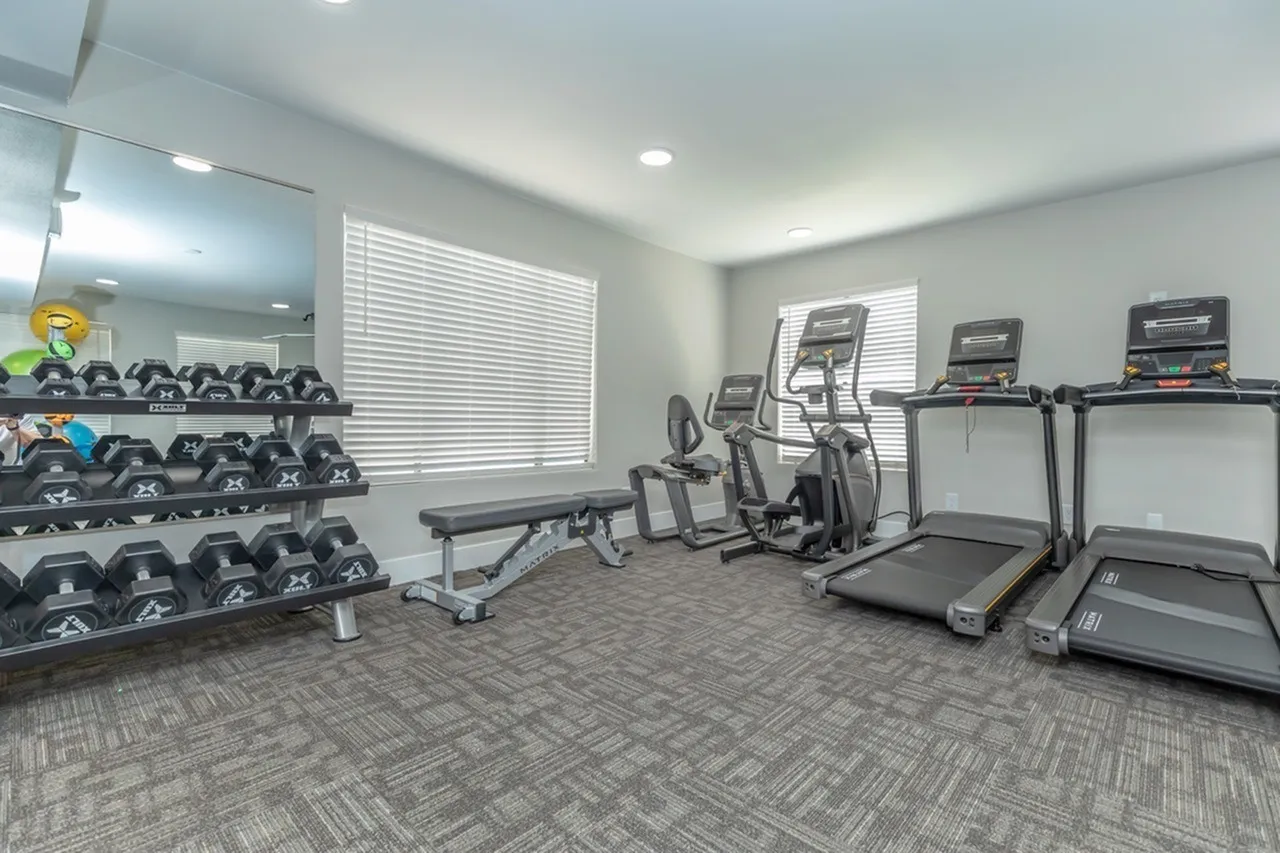 Fitness center, dumbbell racks, treadmills, elliptical machines, mirrored walls