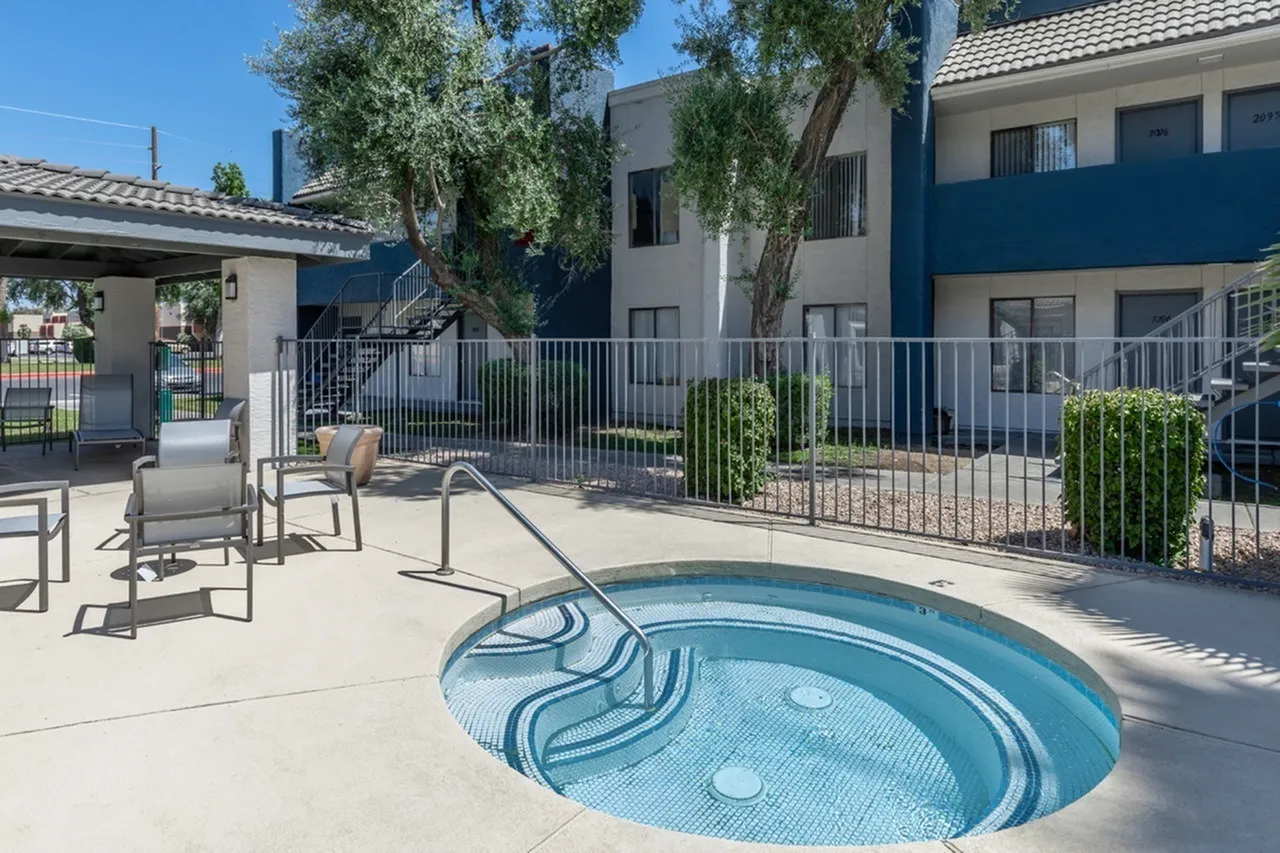 Spa with blue tile, lounge seating, fenced courtyard, apartment buildings, landscaping