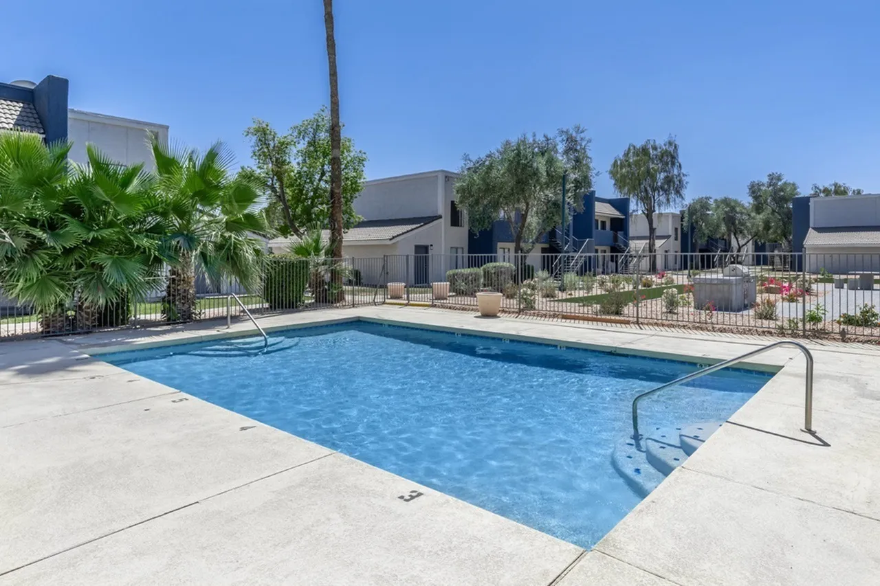 Resort-style swimming pool, concrete deck, metal railings, palm trees, landscaped grounds