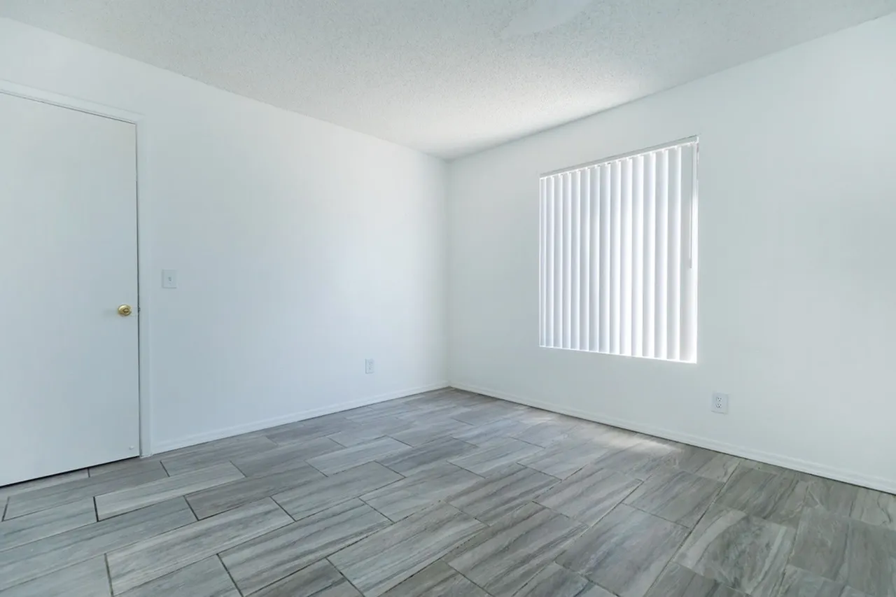 Bedroom, wood-style plank flooring, white walls, vertical blinds, entry door