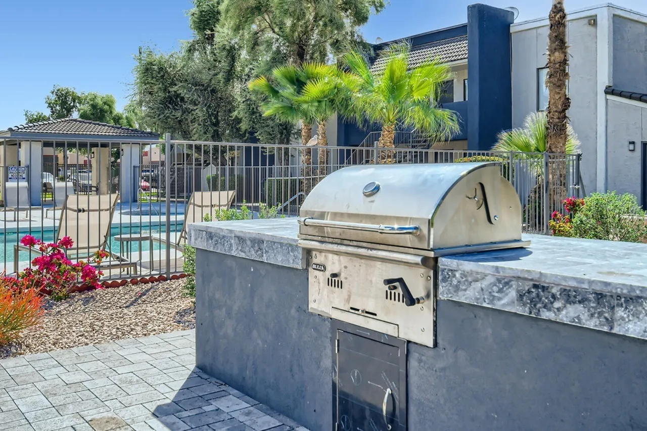 Outdoor grill area, stainless steel grill, concrete countertops, paver patio, palm trees