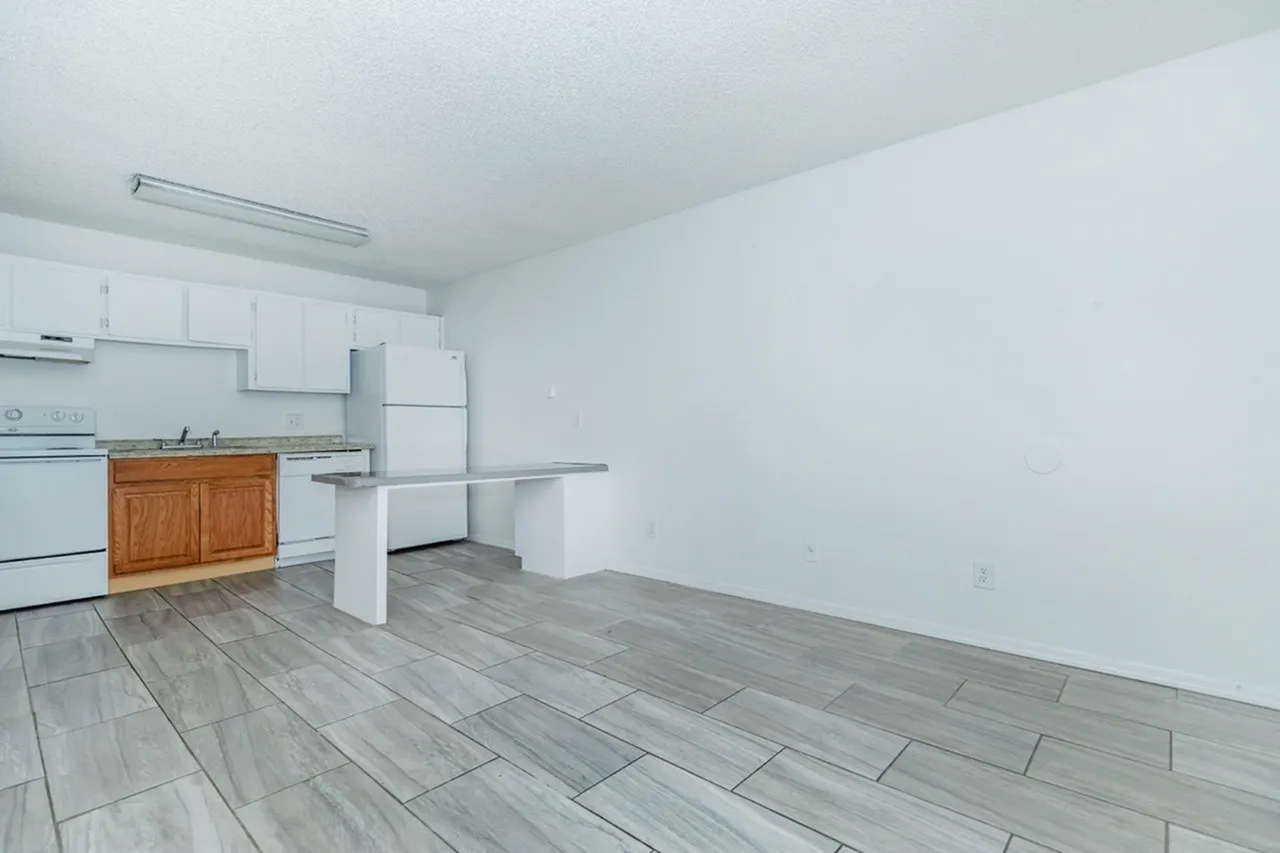 Kitchen with wood cabinetry, stainless appliances, white countertops, wood-style plank flooring, dining space