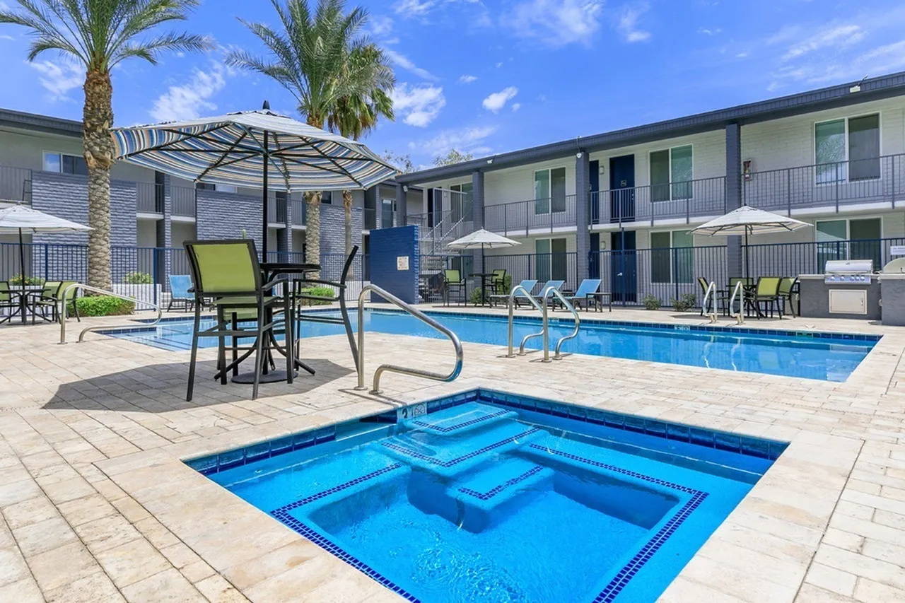 Pool and spa, lounge chairs, umbrellas, palm trees, patio seating