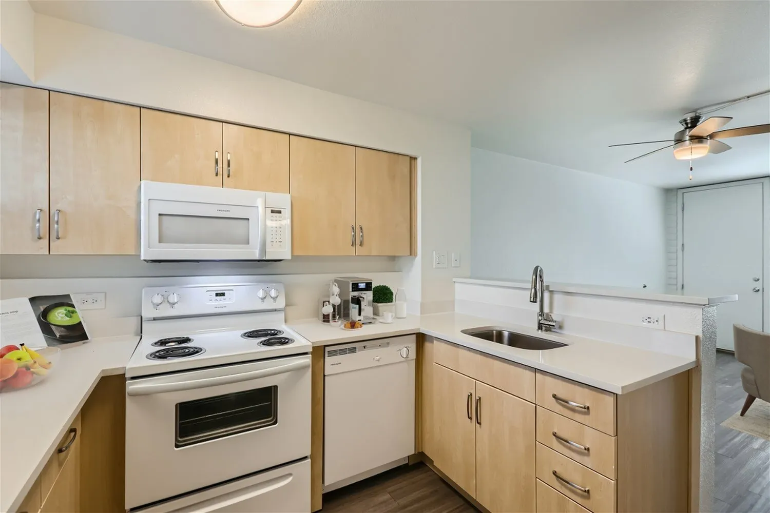 Kitchen, light wood cabinetry, white quartz countertops, white appliances, island with sink