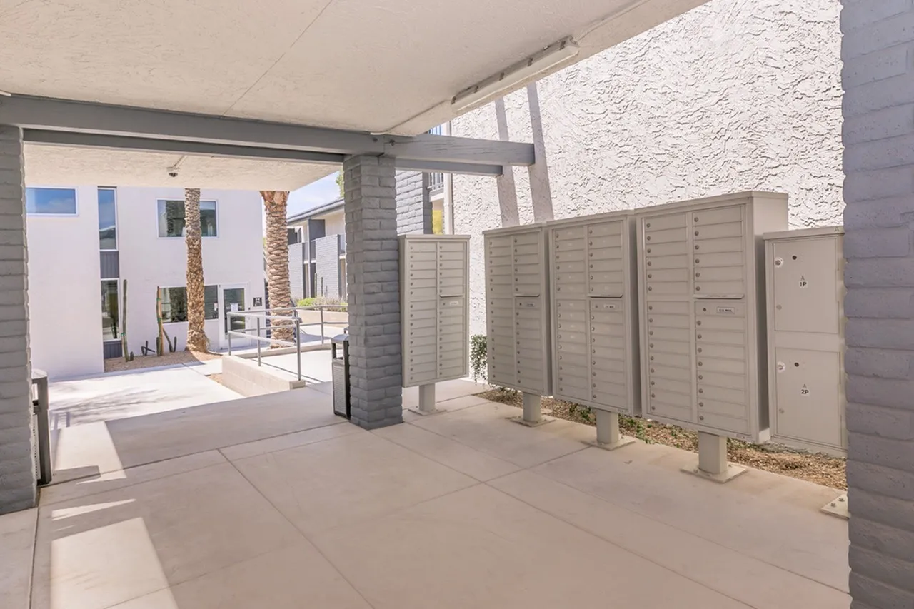 Covered breezeway, clustered mailboxes, concrete paving, building entries