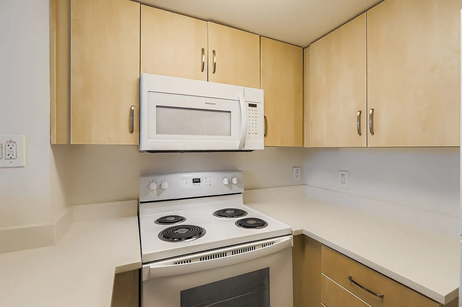 Kitchen, natural wood cabinetry, white appliances, cream countertops