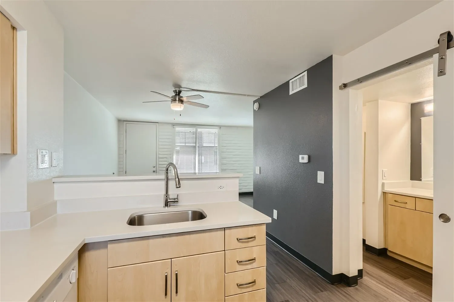 Kitchen, natural wood cabinetry, white quartz countertops, stainless sink, ceiling fan, dark accent wall