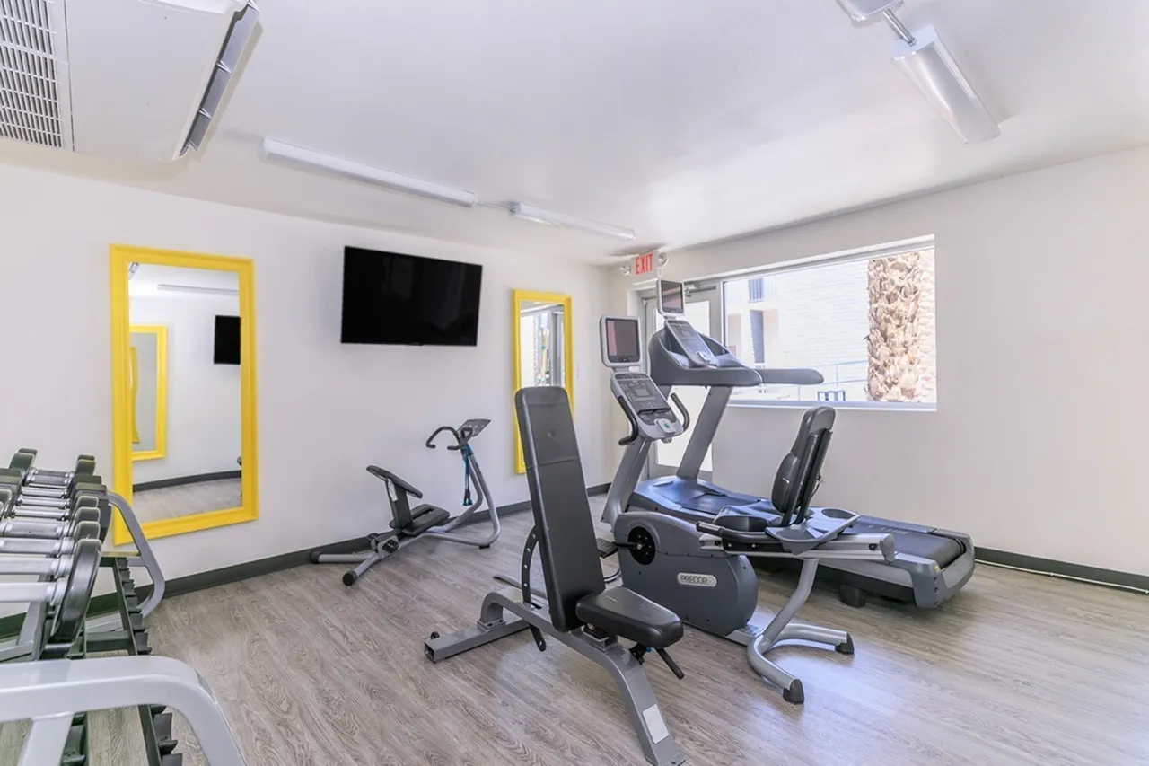 Fitness center with cardio equipment, stationary bikes, treadmill, wood-style plank flooring, TV