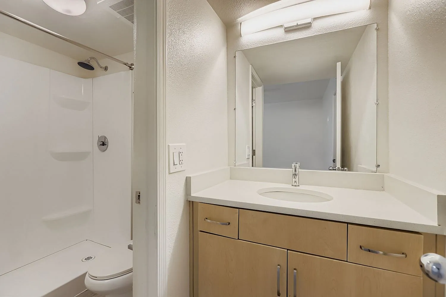 Bathroom, wood-look vanity cabinetry, white quartz countertop, framed mirror, shower enclosure