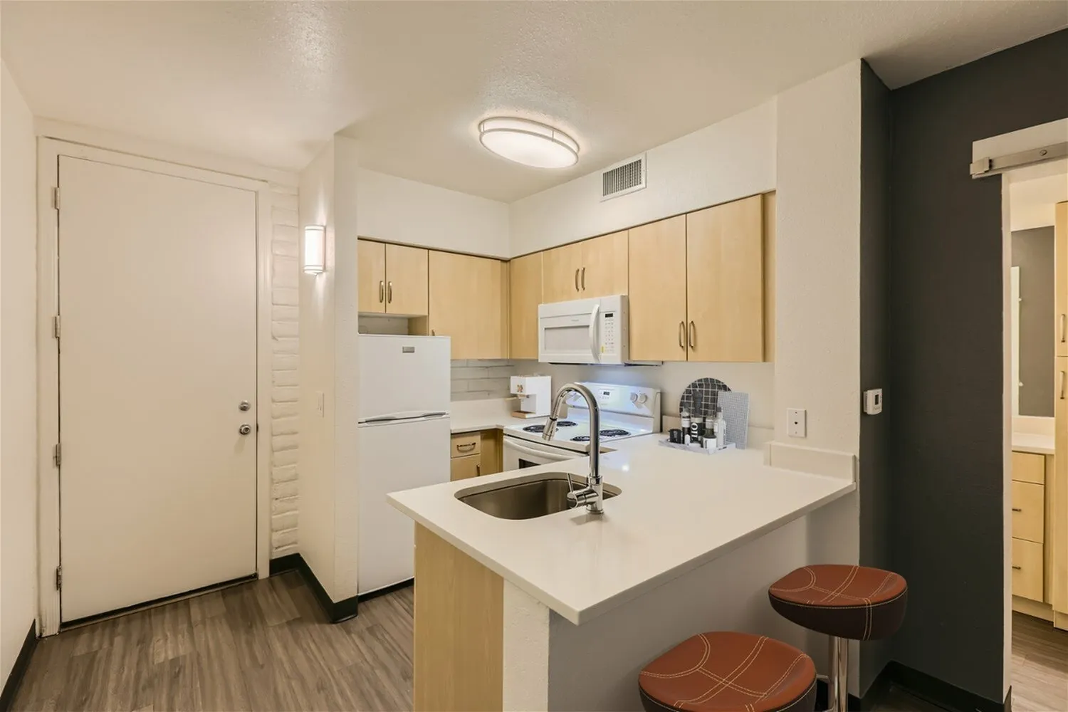 Kitchen, light wood cabinetry, white quartz countertops, white appliances, wood-style plank flooring, breakfast bar with seating