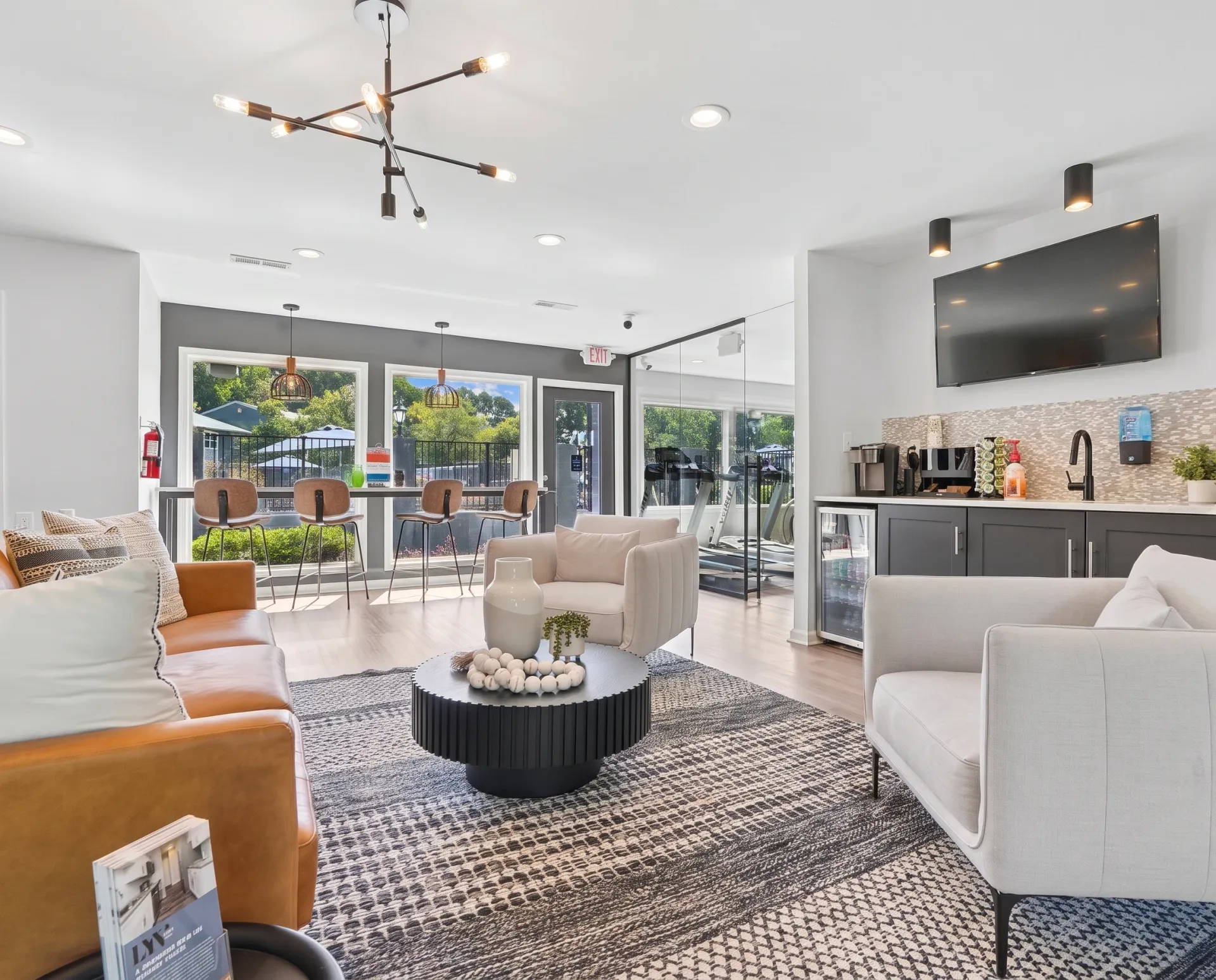 Lounge area, upholstered seating, wood-style plank flooring, ceiling fan, kitchen visible