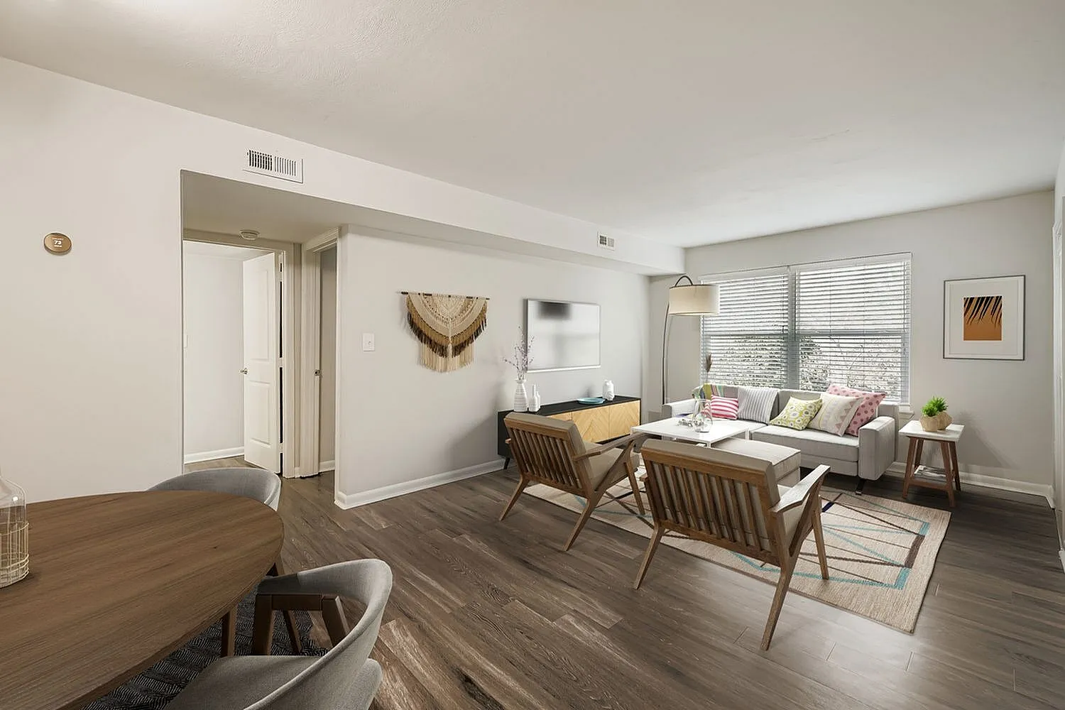 Living room with wood-style plank flooring, mid-century modern seating, windows with blinds, dining table