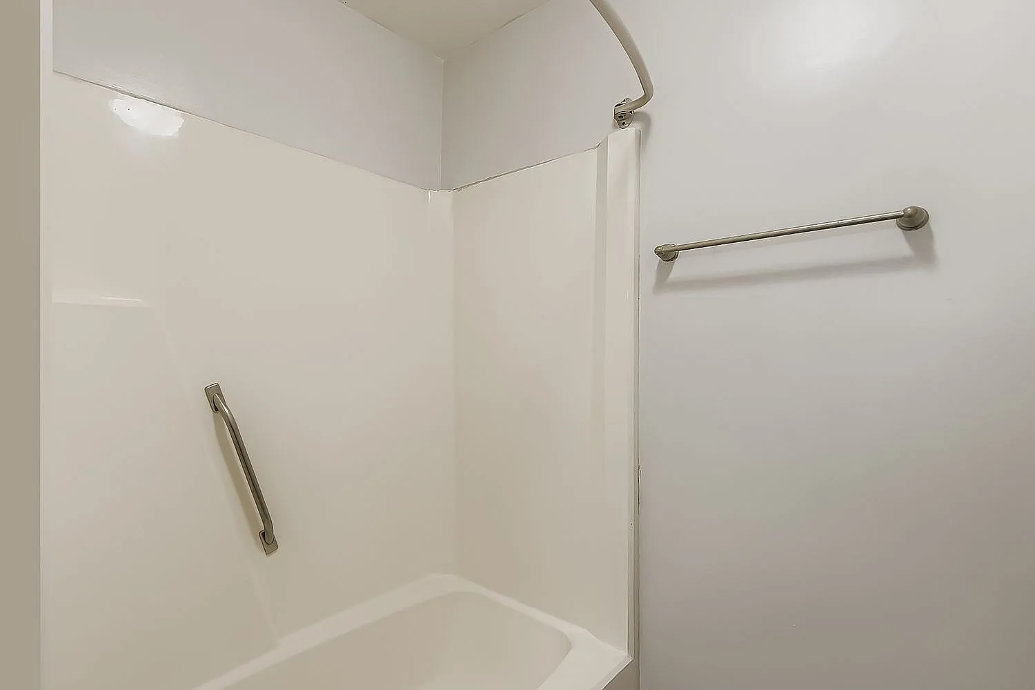 Shower enclosure, white subway tile walls, brushed nickel grab bars and towel bar